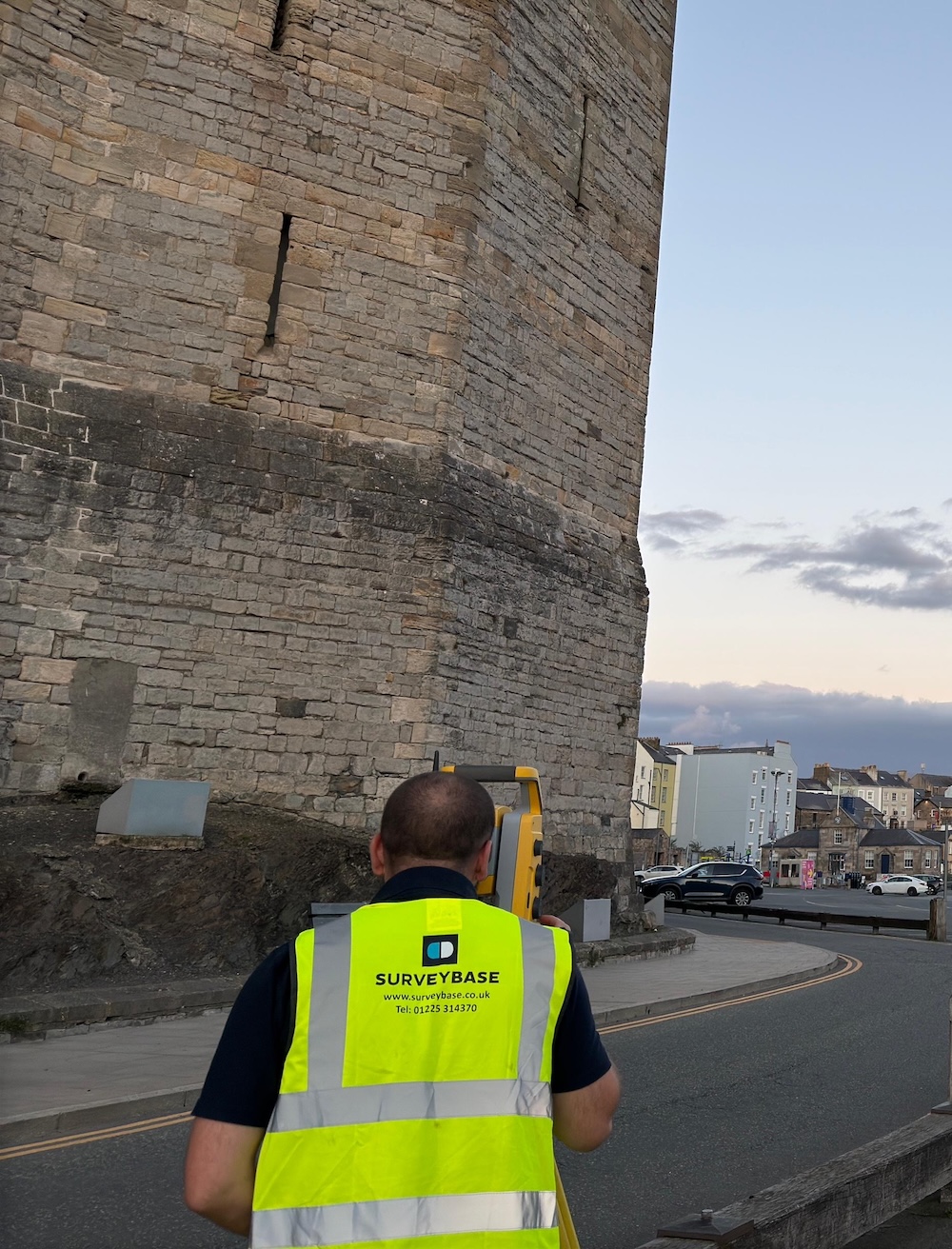 urveyor using equipment beside a castle for a land registry survey.